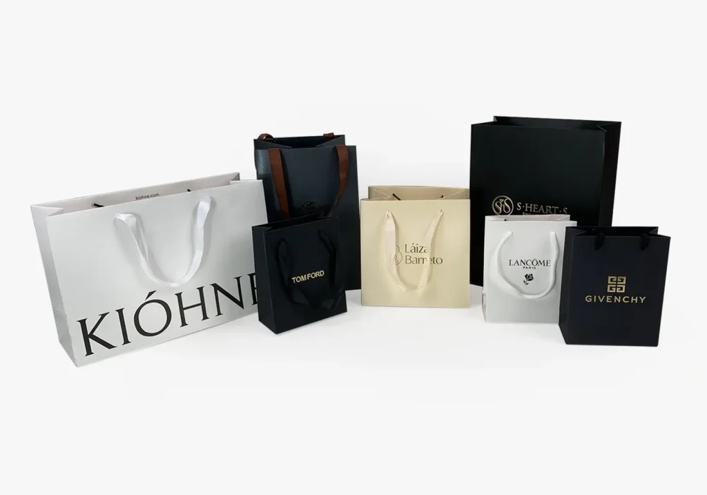 Assorted luxury custom paper bags with printed brand logos.
