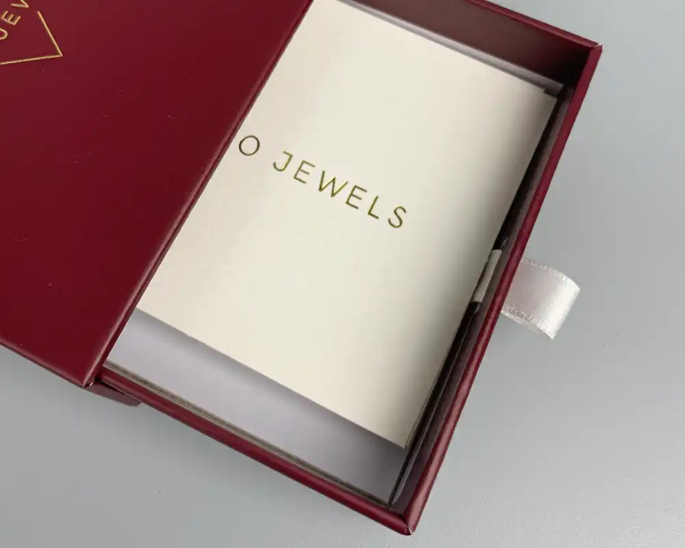 Red custom drawer box with ribbon pull tab and gold logo.