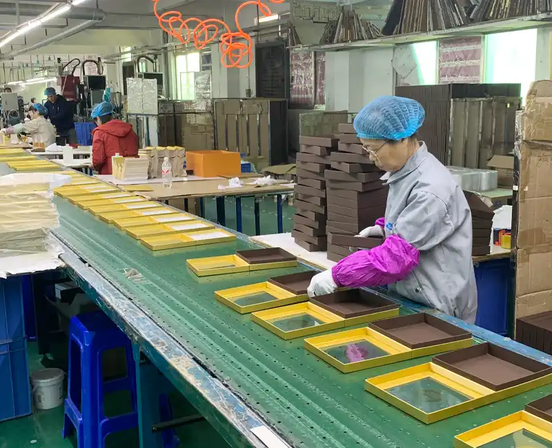 Workers handcrafting luxury rigid boxes on production line.