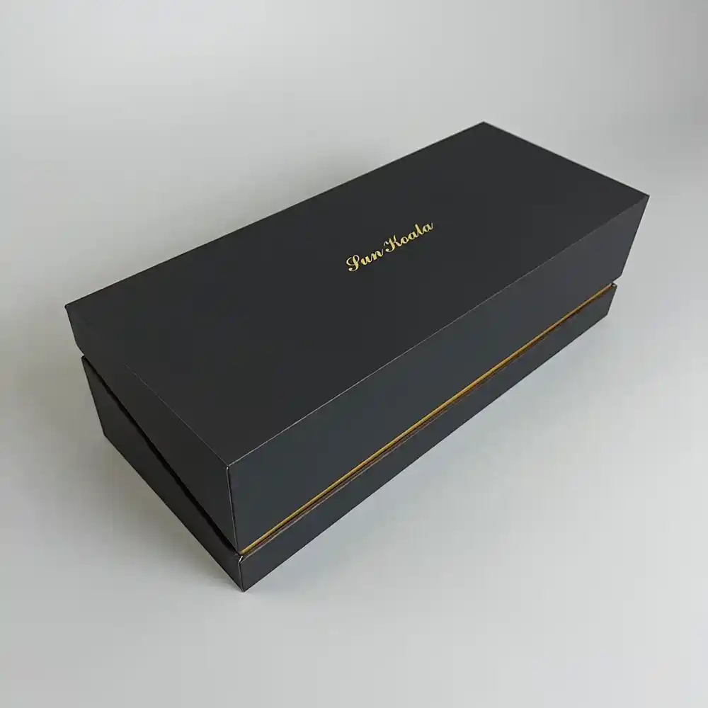 Closed black flip-top rigid gift box with gold foil logo and trim.