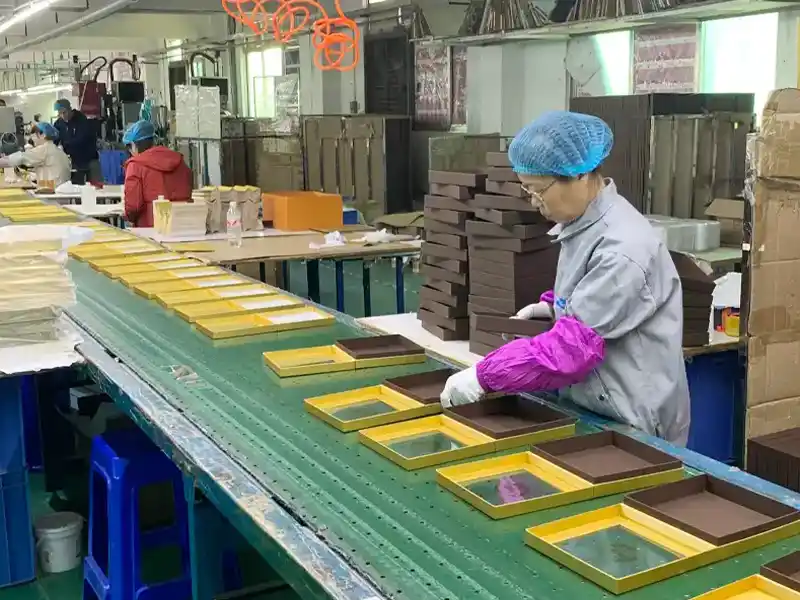 Workers assembling luxury rigid gift boxes on a factory production line.