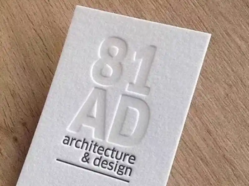 White business card with deep embossed “81 AD” architectural logo.