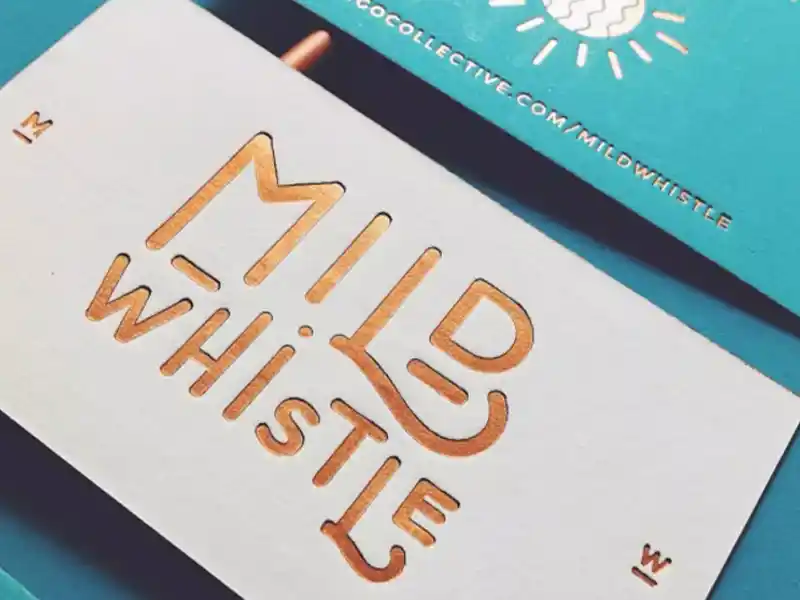 White business card with copper foil embossed “Mild Whistle” logo.