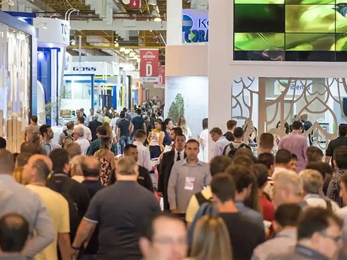 Crowded exhibition hall with visitors exploring paper packaging and printing trade show booths.