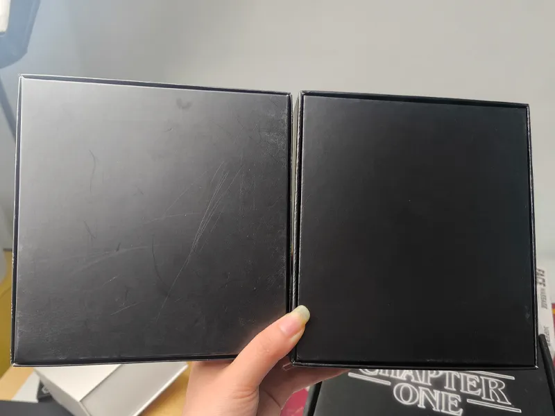 Two black rigid gift boxes side by side, with visible scratches on the left box and an anti-scratch laminated finish on the right box.