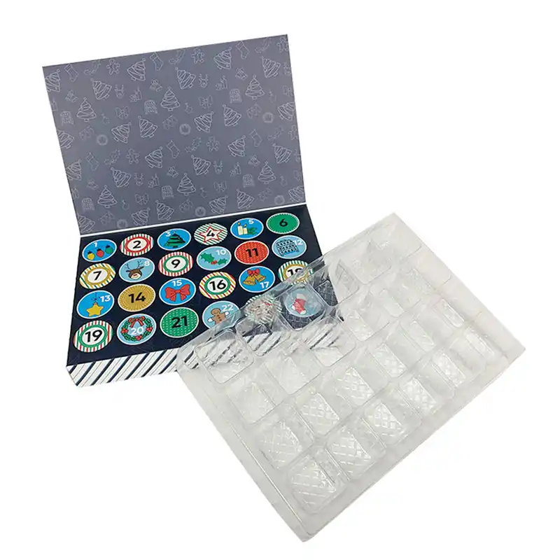 Open Advent calendar with 24 illustrated numbered doors shown beside a clear formed cavity tray for organizing individual contents.